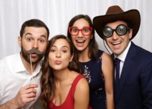 Top Wedding Photo Booth Poses Four wedding guests pose playfully in photo booth with props
